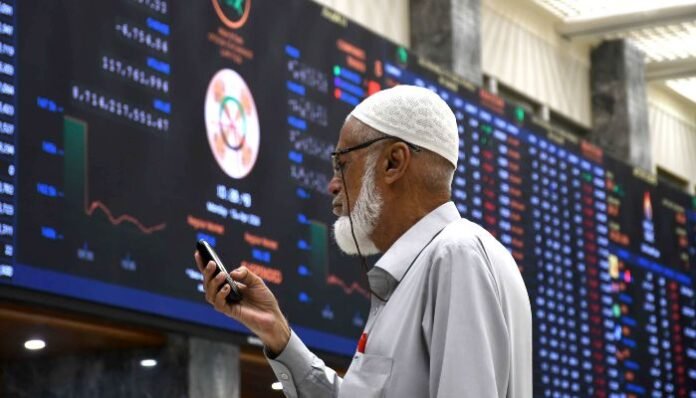 Electronic trading board at the Pakistan Stock Exchange displaying rising stock prices with investors monitoring market activity