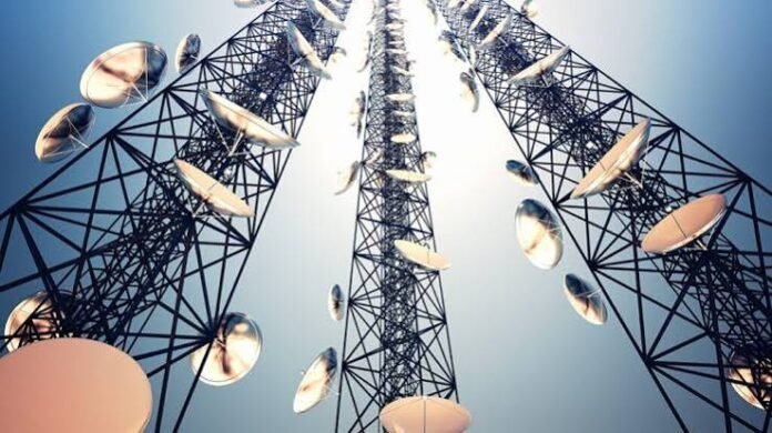 Workers installing fiber-optic telecom infrastructure with mobile towers in the background, representing digital connectivity and economic development.