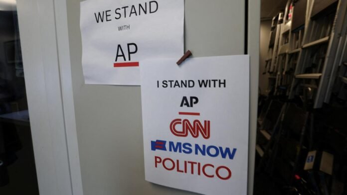 Donald Trump speaks at a White House podium as empty press chairs and television cameras remain in the foreground